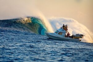 Boat navigating a large wave with people on board
