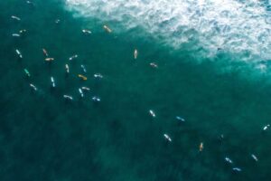 Aerial view of surfers paddling on surfboards in the ocean.