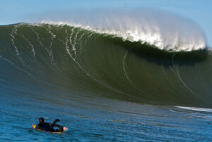 A large wave in the ocean with a person surfing on it, captured as a wall art photo print.
