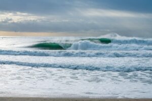 Ocean waves crashing on a beach with a cloudy sky