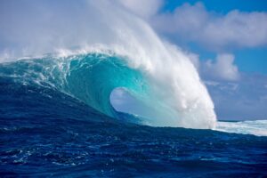 Large big ocean wave with white foam curling over itself against a blue sky, mavericks, jaws, photo