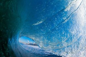 Surfing inside a tube with a cityscape visible through the wave