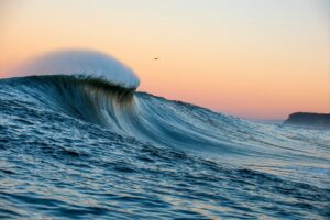 Mavericks big wave in the ocean with a pink sky at sunset for sale