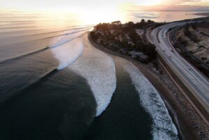 Aerial view of a coastal road with waves and sunset