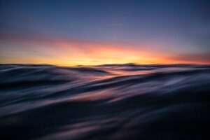 Waves on a body of water with a colorful sunset sky