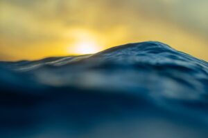 This stunning fine art photograph captures the vastness of the ocean as it ripples in shades of midnight blue, forming massive waves that evoke the ocean’s immense power.
