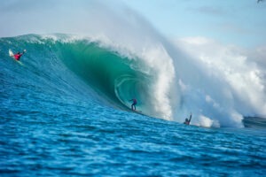 A surfer riding a large wave on a sunny day with the ocean around.